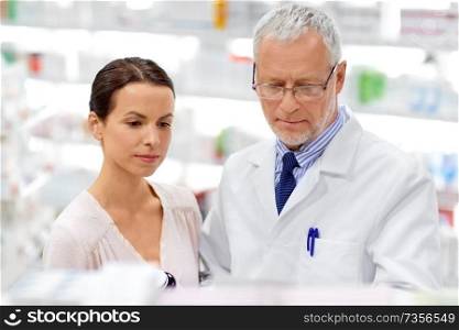 medicine, healthcare and people concept - senior apothecary with drug and female customer at pharmacy. apothecary and woman with drug at pharmacy