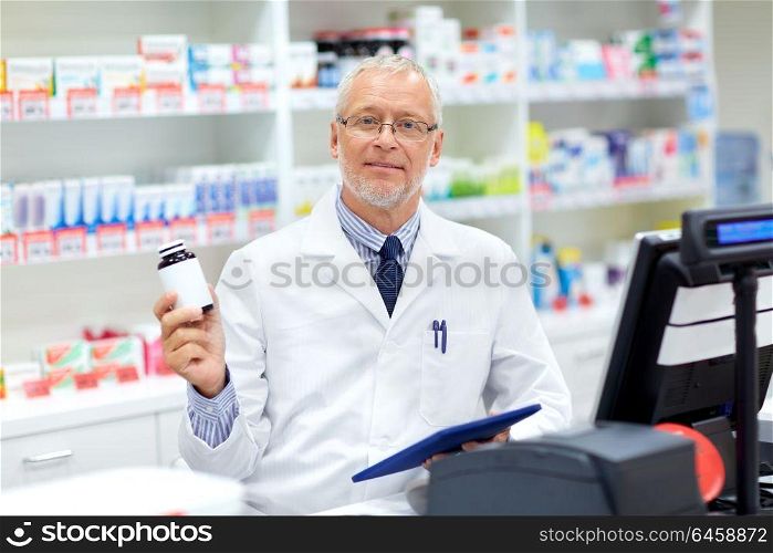 medicine, healthcare and people concept - senior apothecary with drug at pharmacy cash register. senior apothecary with drug at pharmacy