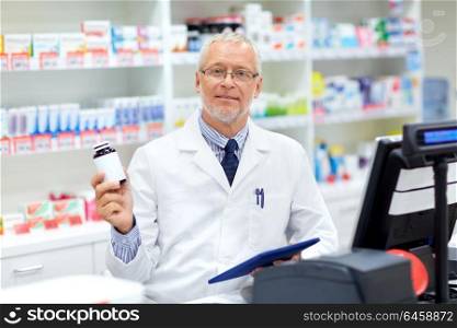 medicine, healthcare and people concept - senior apothecary with drug at pharmacy cash register. senior apothecary with drug at pharmacy