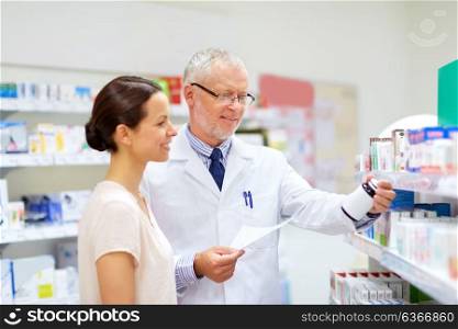 medicine, healthcare and people concept - senior apothecary with drug prescription and female customer at pharmacy. apothecary and woman with drug at pharmacy