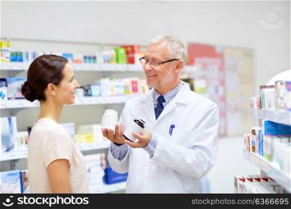 medicine, healthcare and people concept - senior apothecary with drugs and female customer at pharmacy. apothecary and woman with drug at pharmacy