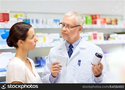medicine, healthcare and people concept - senior apothecary with drugs and female customer at pharmacy. apothecary and woman with drug at pharmacy