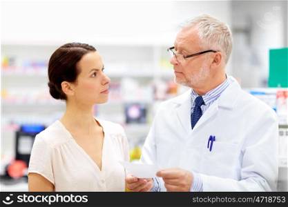 medicine, healthcare and people concept - senior apothecary with prescription talking to female customer at pharmacy. apothecary and woman with prescription at pharmacy. apothecary and woman with prescription at pharmacy