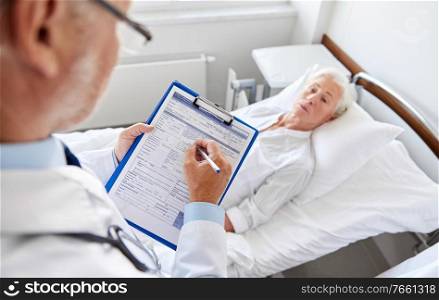 medicine, healthcare and people concept - senior woman and doctor writing to clipboard at hospital ward. senior woman and doctor with clipboard at hospital