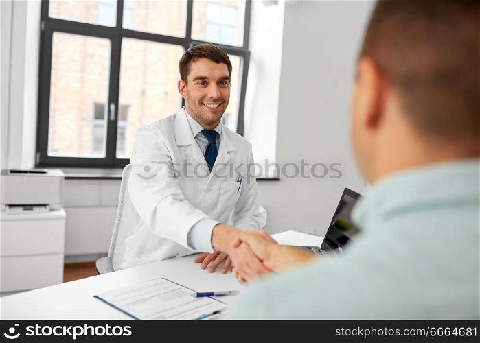 medicine, healthcare and people concept - smiling doctor and male patient shaking hands at hospital. doctor and male patient shaking hands at hospital