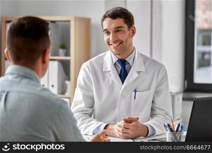 medicine, healthcare and people concept - smiling doctor talking to male patient at medical office in hospital. smiling doctor talking to male patient at hospital