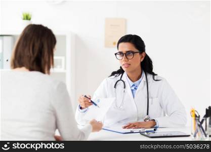 medicine, healthcare and people concept - smiling doctor with clipboard and woman patient at hospital. doctor with clipboard and woman at hospital