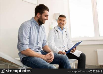 medicine, healthcare and people concept - smiling doctor with clipboard and young man patient meeting at hospital. smiling doctor and young man meeting at hospital
