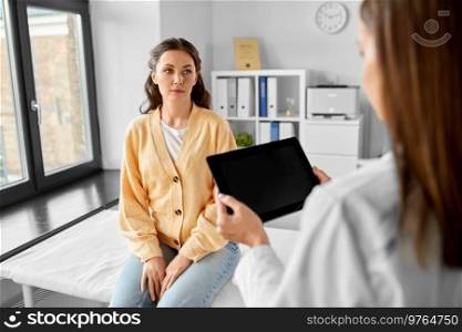 medicine, healthcare and people concept - smiling female doctor showing tablet pc computer to woman patient at hospital. female doctor shows tablet pc to woman at hospital