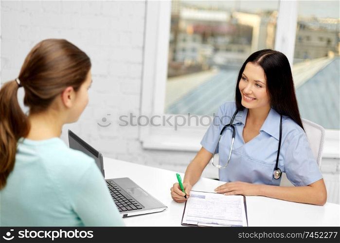 medicine, healthcare and people concept - smiling female doctor with clipboard and woman patient at hospital. female doctor with clipboard and patient at clinic