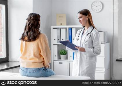 medicine, healthcare and people concept - smiling female doctor with clipboard talking to woman patient at hospital. doctor with clipboard and woman at hospital
