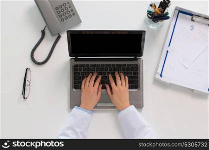 medicine, healthcare and people concept - woman doctor hands typing laptop computer at table in clinic. woman doctor hands typing on laptop at clinic