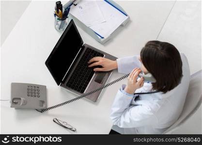 medicine, healthcare and people concept - woman doctor with laptop computer calling on phone sitting at table in clinic. doctor with laptop calling on phone at clinic