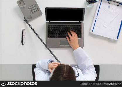medicine, healthcare and people concept - woman doctor with laptop computer calling on phone sitting at table in clinic. doctor with laptop calling on phone at clinic