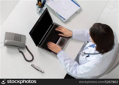 medicine, healthcare and people concept - woman doctor with prescription typing laptop computer sitting at table in clinic. woman doctor typing on laptop at clinic