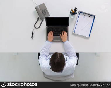 medicine, healthcare and people concept - woman doctor with prescription typing laptop computer sitting at table in clinic. woman doctor typing on laptop at clinic