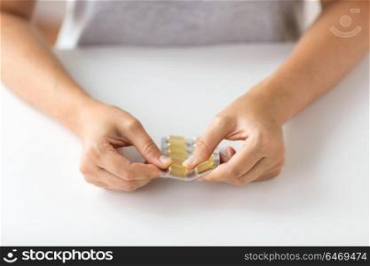 medicine, healthcare and people concept - woman hands opening pack of cod liver oil capsules. woman hands opening pack of medicine capsules