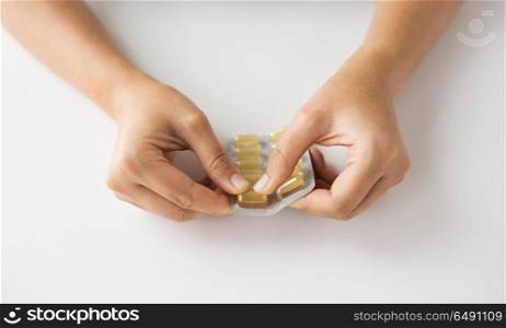 medicine, healthcare and people concept - woman hands opening pack of cod liver oil capsules. woman hands opening pack of medicine capsules. woman hands opening pack of medicine capsules