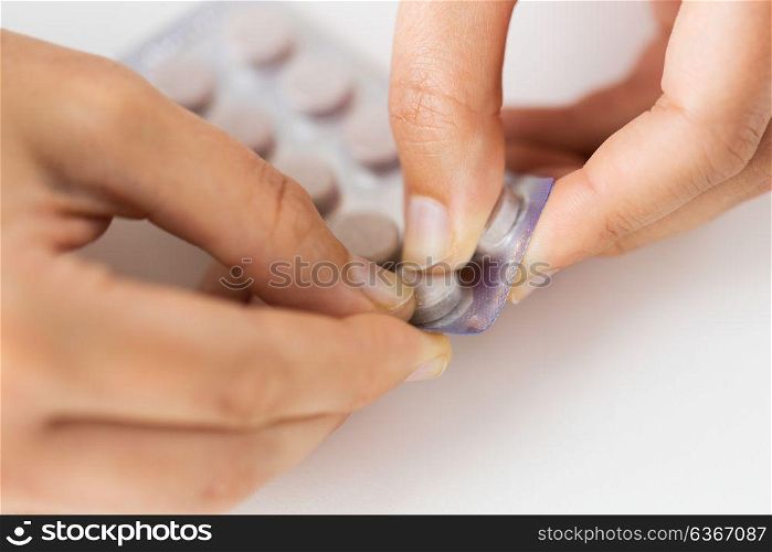 medicine, healthcare and people concept - woman hands opening pack of pills. woman hands opening pack of medicine pills
