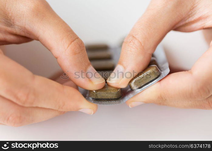 medicine, healthcare and people concept - woman hands opening pack of pills. woman hands opening pack of medicine pills