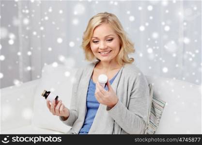 medicine, healthcare and people concept - woman looking at jars with medication at home over snow