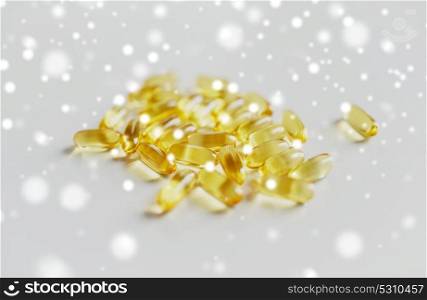 medicine, healthcare and pharmaceutics concept - cod liver oil or omega 3 gel capsules over snow. medicine or cod liver oil capsules
