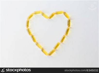 medicine, healthcare and pharmacy concept - cod liver oil capsules in shape of heart. cod liver oil capsules in shape of heart