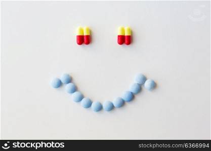 medicine, healthcare and pharmacy concept - different pills and capsules of drugs in shape of smiley. smiley of different pills and capsules of drugs