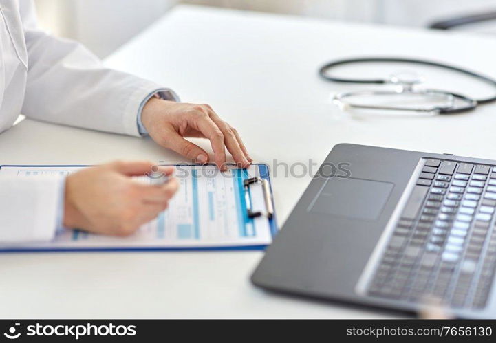medicine, healthcare and profession concept - female doctor in white coat with laptop computer and medical report at hospital. doctor with laptop and medical report at hospital