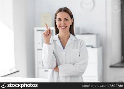 medicine, healthcare and profession concept - smiling female doctor pointing finger up at hospital. happy female doctor pointing finger up at hospital