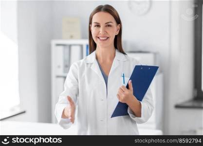 medicine, healthcare and profession concept - smiling female doctor with clipboard giving her hand for handshake at hospital. smiling female doctor with clipboard at hospital