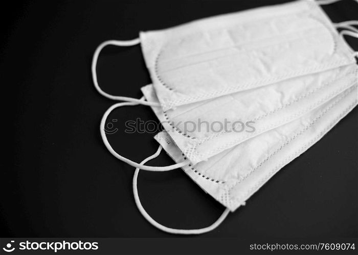 medicine, healthcare and safety concept - close up of white face protective medical masks on black background. close up of white face protective medical masks
