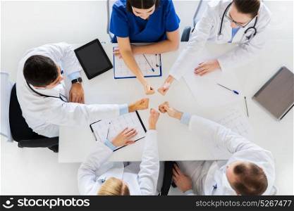 medicine, healthcare and success concept - group of doctors with cardiograms, clipboards and tablet pc computer showing thumbs up over table at hospital. group of doctors showing thumbs up over table