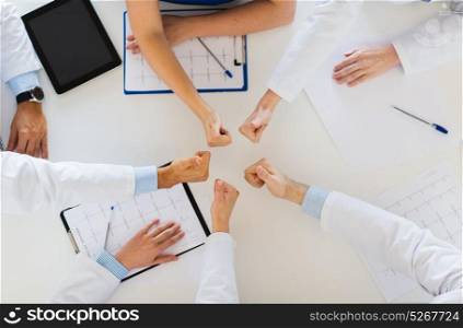 medicine, healthcare and success concept - group of doctors with cardiograms, clipboards and tablet pc computer showing thumbs up over table at hospital. group of doctors showing thumbs up over table