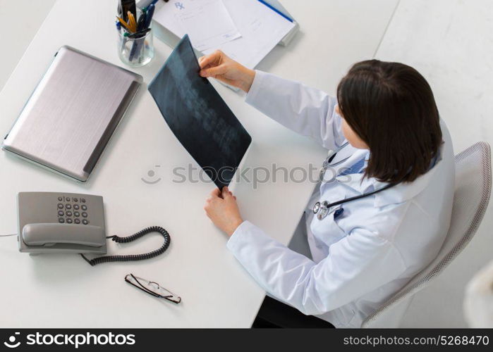 medicine, healthcare and surgery concept - doctor or surgeon with spine x-ray sitting at table. doctor with spine x-ray sitting at table
