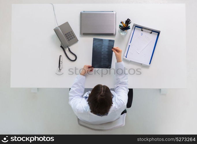 medicine, healthcare and surgery concept - doctor or surgeon with spine x-ray sitting at table. doctor with spine x-ray sitting at table