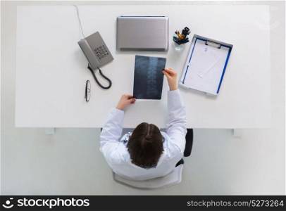 medicine, healthcare and surgery concept - doctor or surgeon with spine x-ray sitting at table. doctor with spine x-ray sitting at table