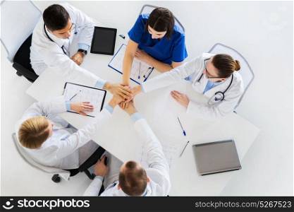 medicine, healthcare and teamwork concept - group of doctors with cardiograms, clipboards and tablet pc computer holding hands together at hospital. group of doctors holding hands together at table