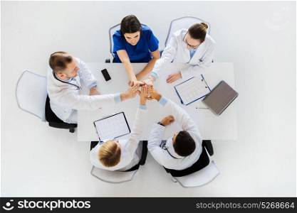 medicine, healthcare and teamwork concept - group of doctors with cardiograms making high five at hospital. group of doctors making high five at table