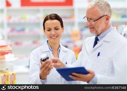 medicine, healthcare and technology concept - apothecaries with tablet pc computer and medication at pharmacy. apothecaries with tablet pc and drug at pharmacy