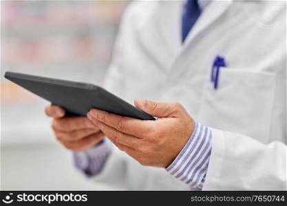 medicine, healthcare and technology concept - close up of senior pharmacists with tablet pc computer at pharmacy. close up of senior pharmacist with tablet pc
