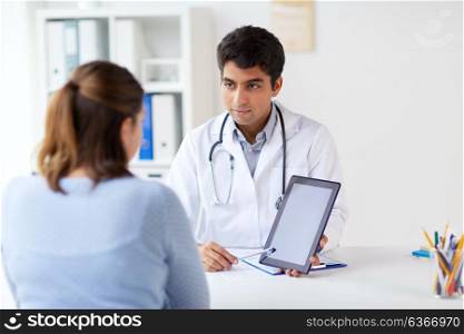 medicine, healthcare and technology concept - doctor showing tablet pc computer to patient at hospital. doctor showing tablet pc to patient at clinic