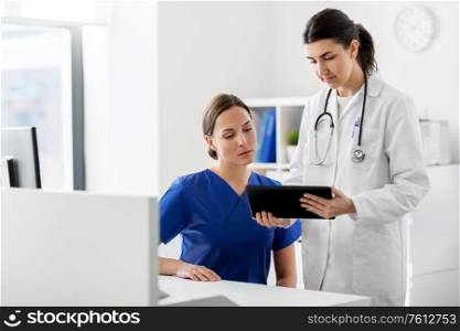 medicine, healthcare and technology concept - doctor with tablet pc computer talking to nurse at hospital. doctor with tablet computer and nurse at hospital