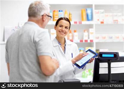 medicine, healthcare and technology concept - happy apothecary and senior male customer with digital prescription on tablet pc computer screen at pharmacy. apothecary and customer with tablet pc at pharmacy. apothecary and customer with tablet pc at pharmacy