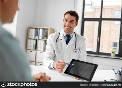 medicine, healthcare and technology concept - happy doctor with tablet pc computer and male patient talking at medical office in hospital. doctor with tablet computer and patient at clinic