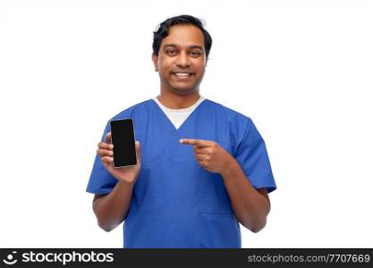 medicine, healthcare and technology concept - happy smiling indian doctor or male nurse in blue uniform with smartphone over white background. smiling doctor or male nurse with smartphone