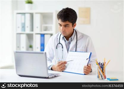 medicine, healthcare and technology concept - male doctor with laptop computer, cardiogram and stethoscope at clinic. doctor with laptop and cardiogram at clinic