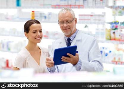 medicine, healthcare and technology concept - senior apothecary and female customer with tablet pc computer at pharmacy. apothecary and customer with tablet pc at pharmacy. apothecary and customer with tablet pc at pharmacy