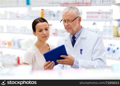 medicine, healthcare and technology concept - senior apothecary and female customer with tablet pc computer at pharmacy. apothecary and customer with tablet pc at pharmacy