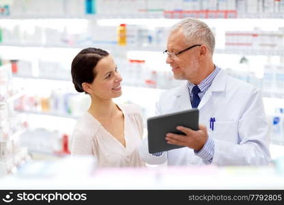 medicine, healthcare and technology concept - senior apothecary and female customer with tablet pc computer at pharmacy. apothecary and customer with tablet pc at pharmacy